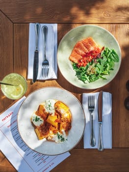 Tortiglioni bolognese pasta or paccheri bolognese and salmon with tomato salsa and ponzu sauce dishes. Tasty food in summer sunny day outdoor of restaurant or cafe terrace, top view or flat lay