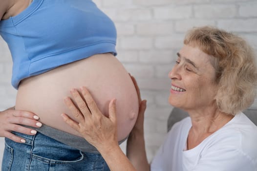 An elderly woman leans against the belly of her pregnant daughter. Close-up
