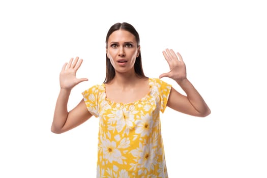 young pretty brunette woman dressed in a summer yellow T-shirt shows her palms.