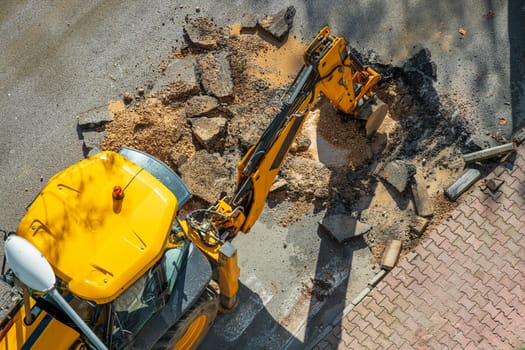 Digger digging asphalt to repair a water fault in a street