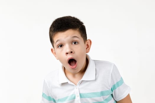 surprised little child boy in t-shirt looking to camera on white background. Human emotions and facial expression