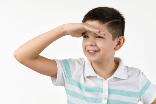 Cute little child boy in striped t-shirt looking into the distance on white background.
