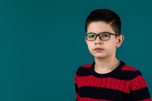 little cheerful caucasian school boy wearing glasses over blue background. copy space