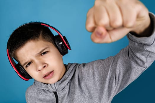 child boy enjoys listens to music in headphones over blue background