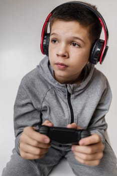 child boy playing video games over gray background. young gamer playing with game console