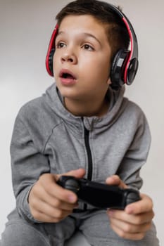 child boy playing video games over gray background. young gamer playing with game console. Someone distracts a guy from playing games