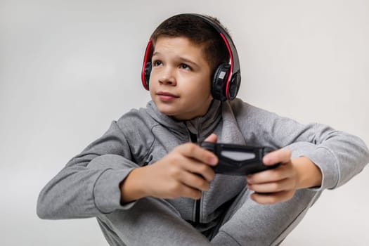 child boy playing video games over gray background. young gamer playing with game console