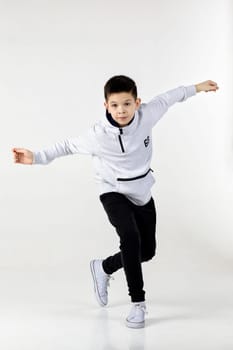 Little hip-hop boy dancing on white studio background. sports dance