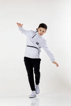 Little hip-hop boy dancing on white studio background.