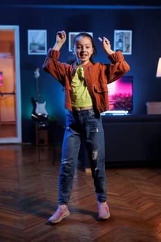 Popular child takes part in viral dance trend after seeing favorite celebrities doing it, filming family channel video in apartment for children audience. Smiling kid does trendy dancing challenge
