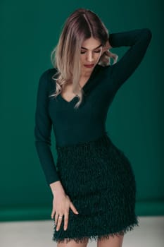 Sensual beautiful blonde woman posing in green dress on green background