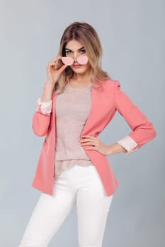 Fashion portrait of attractive elegant blonde woman in pastel casual pink jacket posing in studio. woman dressed in trendy spring outfit