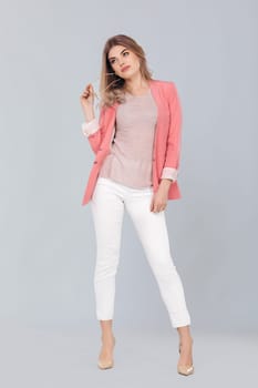 Full length portrait of attractive elegant blonde woman in pastel pink jacket posing in studio. woman dressed in trendy spring outfit