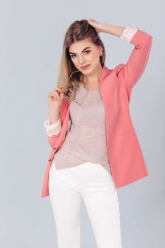Fashion portrait of attractive elegant blonde woman in pastel casual pink jacket posing in studio. woman dressed in trendy spring outfit