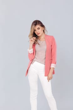 Fashion portrait of attractive elegant blonde woman in pastel casual pink jacket posing in studio. woman dressed in trendy spring outfit