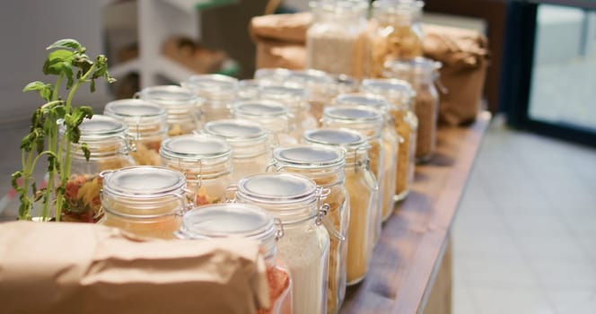 Close up on bulk food items in glass jars used by environmentally friendly zero waste store to lower climate impact. Local organic shop with natural ingredients pasta, spices or sauces.