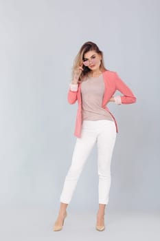 Full length portrait of attractive elegant blonde woman in pastel pink jacket posing in studio. woman dressed in trendy spring outfit