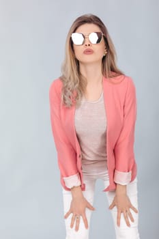 Fashion portrait of attractive elegant blonde woman in pastel pink jacket and sunglasses posing in studio. woman dressed in trendy spring outfit