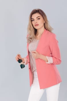 Fashion portrait of attractive elegant blonde woman in pastel casual pink jacket posing in studio. woman dressed in trendy spring outfit