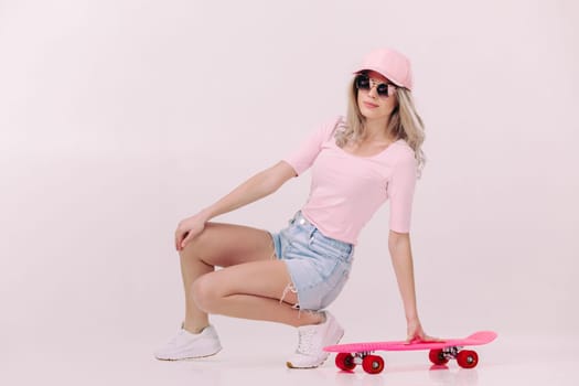 beautiful woman in sunglasses, pink t-shirt and cap with pink skateboard