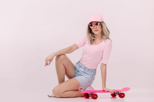 beautiful woman in sunglasses, pink t-shirt and cap with pink skateboard