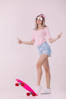 beautiful woman in sunglasses, pink t-shirt and cap with pink skateboard