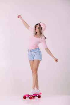 beautiful woman in sunglasses, pink t-shirt and cap stands on pink skateboard