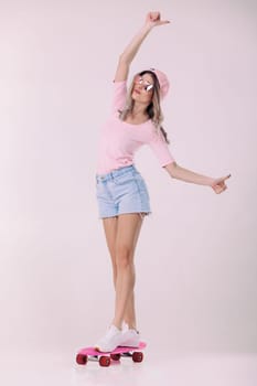 beautiful woman in sunglasses, pink t-shirt and cap stands on pink skateboard