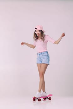 beautiful woman in sunglasses, pink t-shirt and cap stands on pink skateboard