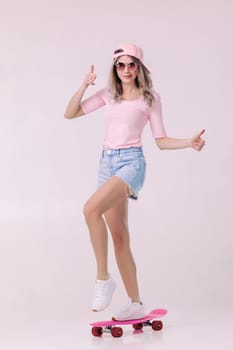 beautiful woman in sunglasses, pink t-shirt and cap stands on pink skateboard