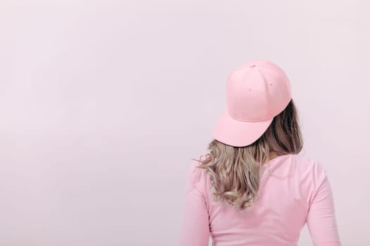 blonde woman in pink t-shirt and pink cap on light background. femininity and spring. copy space.