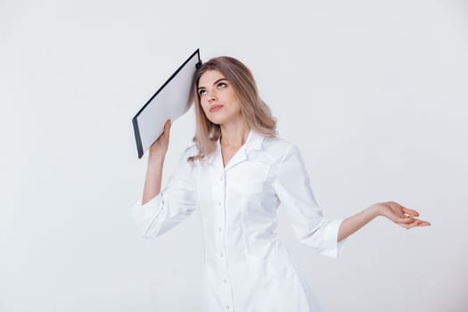 disappointed medical physician doctor woman in white coat holds folder and spreads her arms to the side