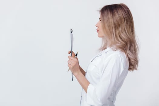 Medical physician doctor woman in white coat holds folder with documents on light background.