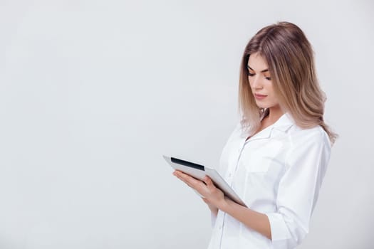 Portrait of beautiful blonde doctor in white coat working on digital tablet