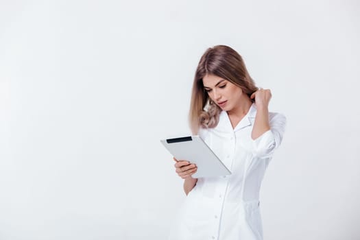 Portrait of beautiful blonde doctor in white coat using digital tablet