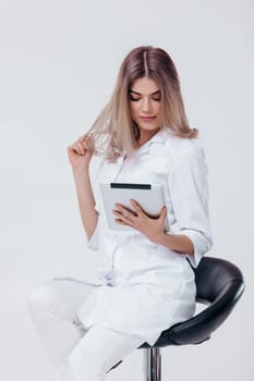 Portrait of beautiful blonde doctor in white coat using digital tablet