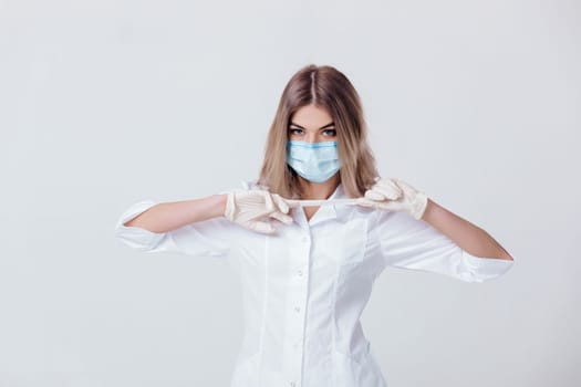 Portrait of woman doctor with face mask takes off white medical gloves
