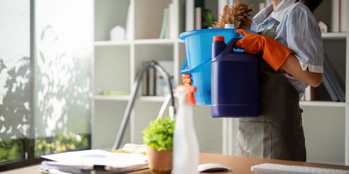 Young woman cleaning to disinfect the office office cleaning staff cleaning maid. Female cleaner holding a bucket with cleaning supplies.