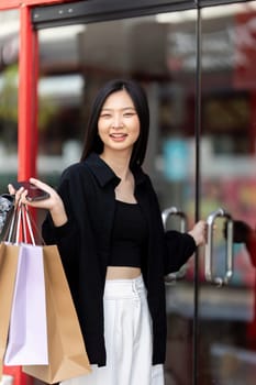 Cheerful Beautiful Asian woman holding shopping bags in shopping in the city on holiday Black Friday.