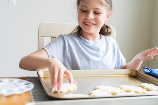 A heartwarming scene of a little girl carefully writing 'Sorry' on sugar cookies with food coloring, the cookies beautifully flooded with white royal icing.