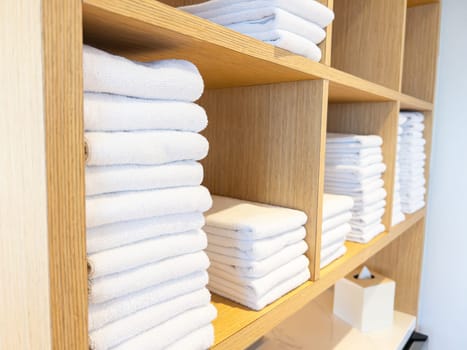 Fluffy white towels orderly arranged on bamboo shelving.