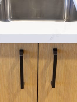 A compact bar area within a hotel's fitness center, featuring a striking geometric backsplash and floating wooden shelves, with a panoramic window offering views of the urban skyline.