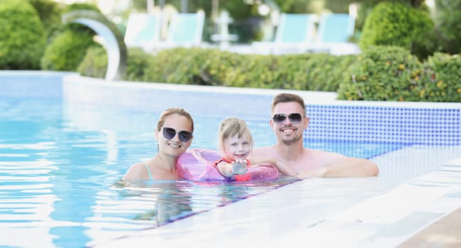 Young family with child in circle in pool on vacation. Wonderful vacation with children abroad concept