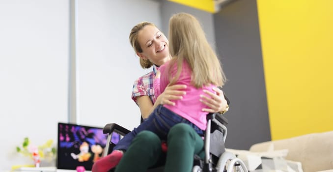 Young woman sitting in wheelchair and hugging her little daughter. Full life of disabled people concept