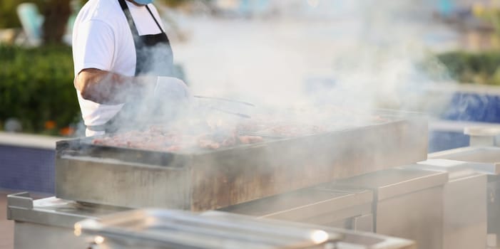 Male chef preparing barbecue on grill in restaurant closeup. Restaurant catering concept