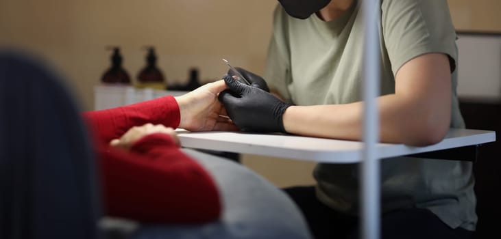 Woman master doing manicure to client in beauty salon. Beauty services concept