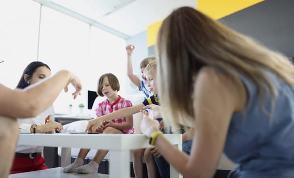 Adults and children playing board games at table at home. Spending time with children concept