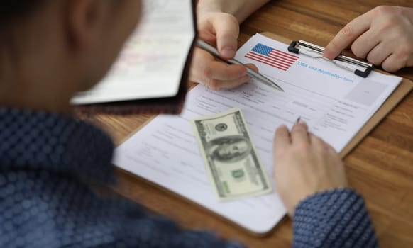 Man filling out paperwork for american visa with help of consultant closeup. Assistance in paperwork for moving to usa concept