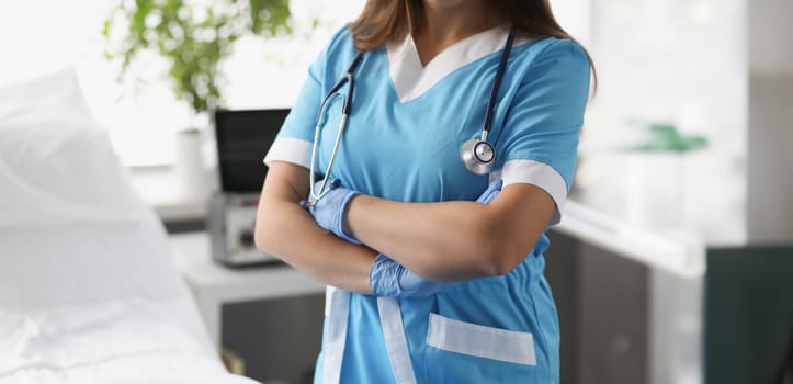 Woman doctor with crossed arms standing in hospital ward closeup. Severe patient care concept