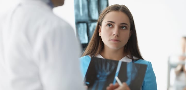 Woman doctor communicating with colleague with xrays in clinic. Teamwork in medicine concept